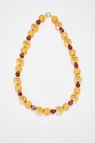 Gold sculptural necklace with red pearl detail
